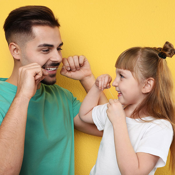 Father and daughter flossing their teeth